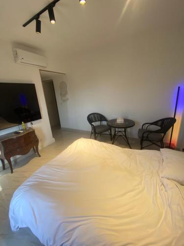 a white bed in a room with chairs and a table at The Vibe in Madinaty