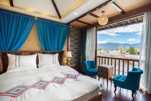 a bedroom with a bed and a balcony with blue chairs at 指云公馆Lijiang Mufu Royal Garden Resort半山观景民宿 in Lijiang
