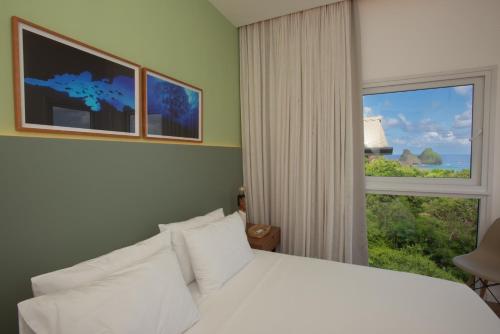 a bedroom with a white bed and a window at Pousada Mar em Mim in Fernando de Noronha