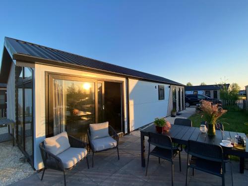 a patio with a table and chairs and a dining table at Elegantes Chalet am Wasser mit Steg Klimaanlage Ferienhaus am See Niederlande in Kampen
