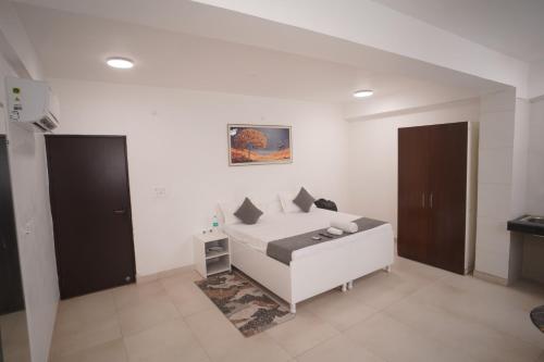 a white bedroom with a bed and a table at Hotel Airport Stay in New Delhi