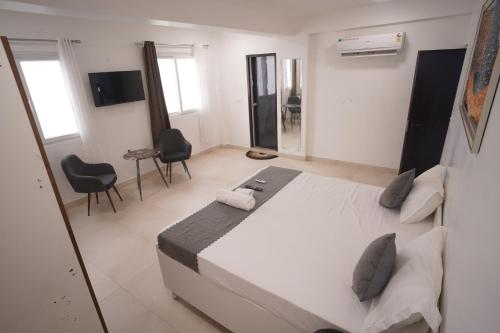 a bedroom with a large white bed and two chairs at Hotel Airport Stay in New Delhi