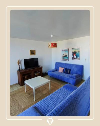 un salon avec des canapés bleus et une table dans l'établissement AGDE : Vue exceptionnelle sur le Fleuve et grand appartement de 2 chambres au cœur du centre historique d'Agde., à Agde