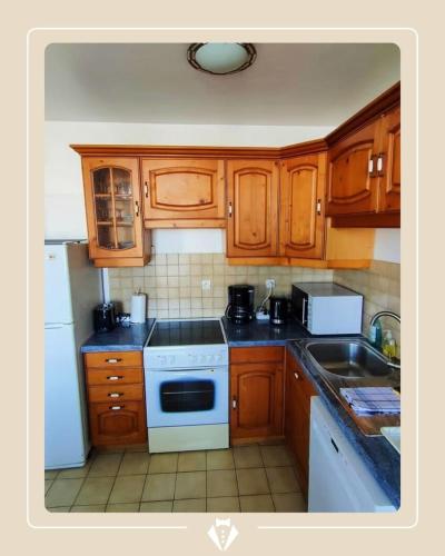 une cuisine avec des armoires en bois et un four blanc dans l'établissement AGDE : Vue exceptionnelle sur le Fleuve et grand appartement de 2 chambres au cœur du centre historique d'Agde., à Agde