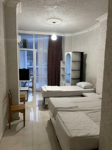 a room with three beds and a television in it at Family hotel Khomaldy in Kvariati