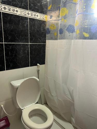 a bathroom with a toilet and a shower curtain at Suite 1, Casa Amarela, Segundo Andar in Nova Iguaçu