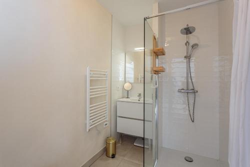 a white bathroom with a shower and a sink at Bel appartement avec jardin proche des plages in Anglet
