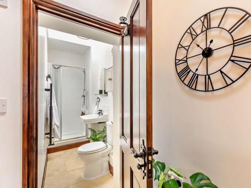 a bathroom with a clock on the wall and a toilet at 1 Bed in Thirsk 94728 in Thirsk