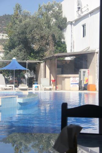 a swimming pool with some chairs and an umbrella at Bodrum Blu Hotel in Bodrum City