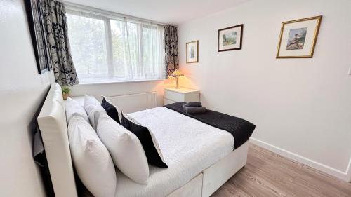 a bedroom with a bed with white sheets and a window at Spacious Maida Vale Apt with Private Garden near Little Venice & Paddington by Staylio London in London