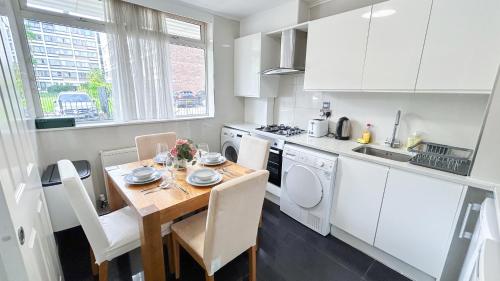a kitchen with a wooden table and a kitchen with white cabinets at Spacious Maida Vale Apt with Private Garden near Little Venice & Paddington by Staylio London in London