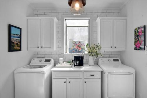 a white laundry room with two washes and a window at 219 Olive Way in East End