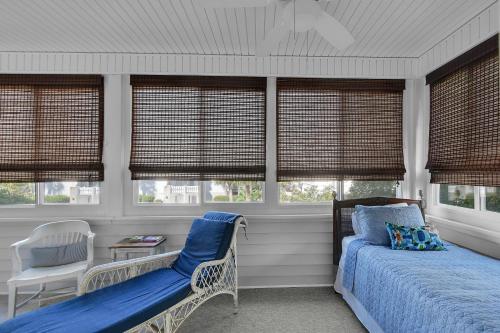 a bedroom with a bed and a chair and windows at 219 Olive Way in East End