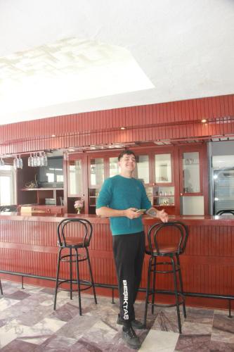 a man standing in front of a bar with two chairs at Bodrum Blu Hotel in Bodrum City