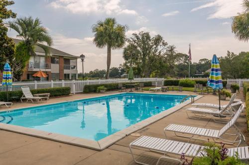 a large swimming pool with lounge chairs and umbrellas at Sea Palms Colony 240D in Glynn Haven
