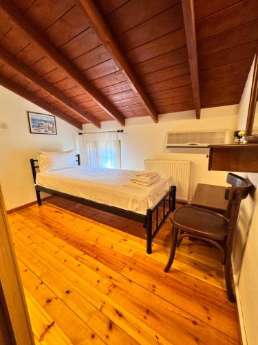 a bedroom with a bed and a chair and wooden floors at Alexaria Holidays Homes in Lefkada