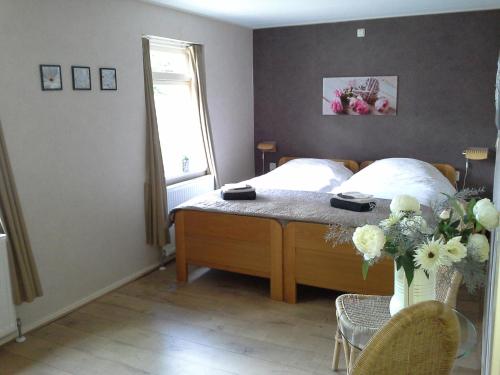 a bedroom with a bed with a vase of flowers at Skoallehus vakantiewoning in De Bult