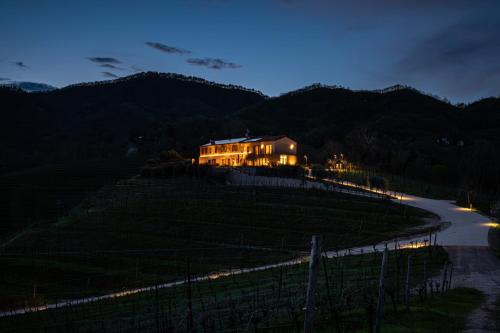 a house on top of a hill at night at Col del Noc - Luxury Apartments & Pool Prosecco Hills in Cozzuolo