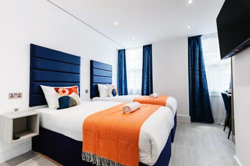 two beds in a hotel room with windows at Upper Berkeley Hotel in London