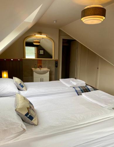 two large white beds in a room with a mirror at Highland Rooms - Room Only No Breakfast in Ullapool