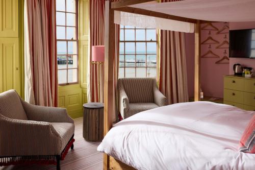 a bedroom with a bed and two chairs and a window at Drakes Hotel in Brighton & Hove