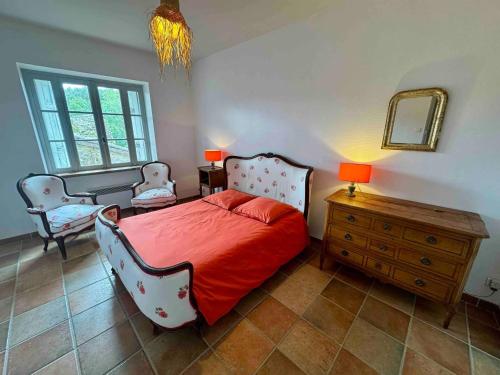 a bedroom with a bed and two chairs and a dresser at Charmante maison à Laure-Minervois avec piscine et jardin in Laure-Minervois