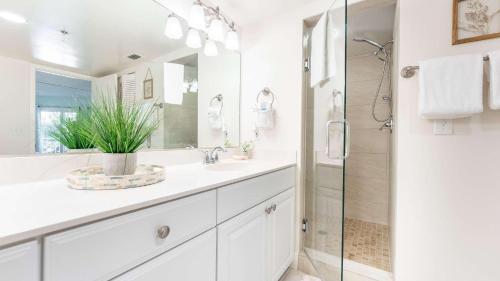 a white bathroom with a sink and a shower at Beach Club 203 in East End