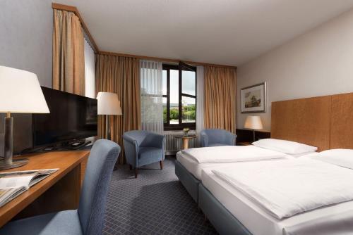 a hotel room with a bed and a desk at Maritim Hotel Am Schlossgarten in Fulda