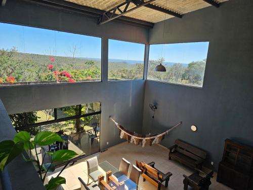 una gran sala de estar con grandes ventanas y una mesa. en Casa completa linda vista, en Chapada dos Guimarães