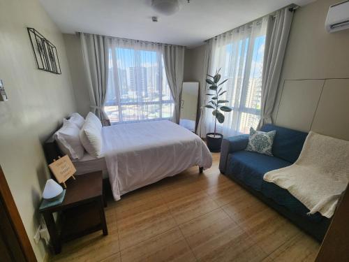 a bedroom with a bed and a blue couch at Cozy 1BR Corner with Panoramic City Skyline View in Manila