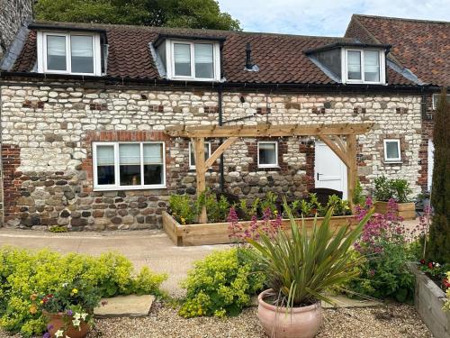 a stone house with a wooden pergola at Low Barn in Bridlington