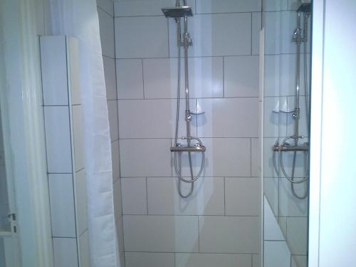 y baño con ducha de azulejos blancos. en Skoallehus vakantiewoning, en De Bult
