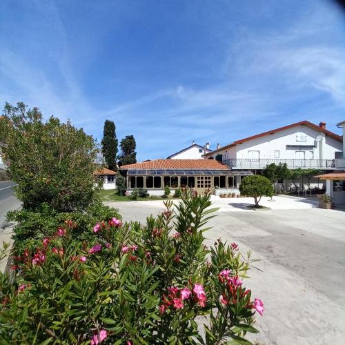 a building with pink flowers in front of a street at Apartment-rooms Preka in Rab