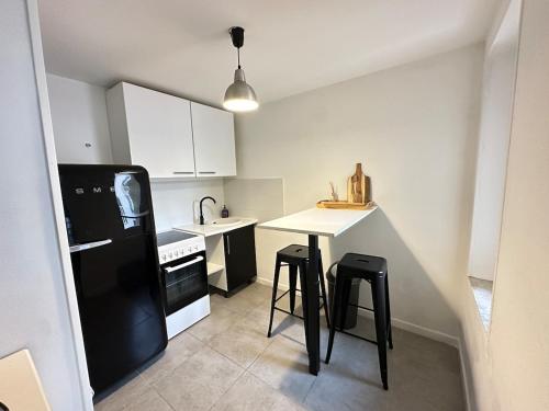 Il comprend une cuisine équipée d'un réfrigérateur noir et d'une table avec des tabourets. dans l'établissement Duplex climatisé - hyper centre - Cœur de Nice, à Nice