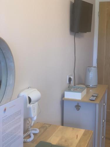 a room with a desk with a phone and a television at The Living Energy Holidays in Velindre