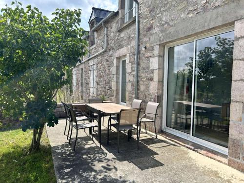a dining table and chairs in front of a stone building at 754 - Maison 3 chambres à 800m de la plage des Montiers in Erquy