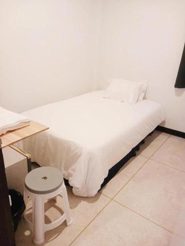 a white bed with a stool in a room at GO INN Asiatique BKK - โกอินน์ เอเชียทีค เจริญกรุง in Godown
