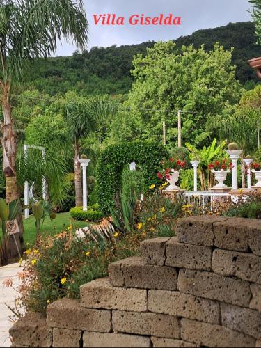 a garden with a stone wall and flowers and trees at Villa Giselda con idromassaggio in Formia