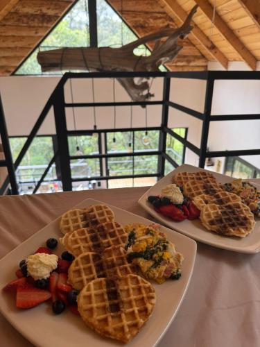 two plates of food on a table with waffles and fruit at Cabaña Malbec - La Cava Lodge in Medellín