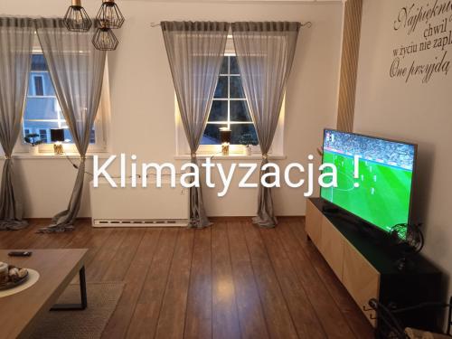 a living room with a flat screen tv and two windows at Apartament Magnolia - Centrum in Nysa