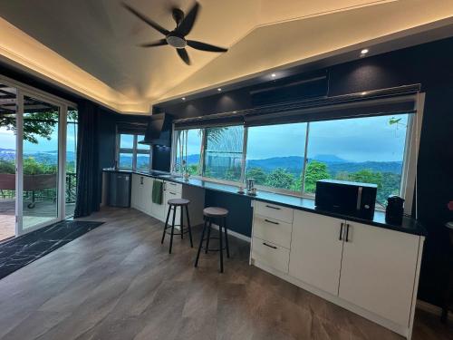a kitchen with a ceiling fan and large windows at Sinurambi Cottage Rental in Penampang