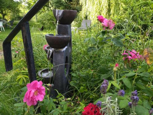 a bird bath in the middle of a garden with flowers at Gite de la Pierre Bleue, Authentique Maison à la campagne in Verdon