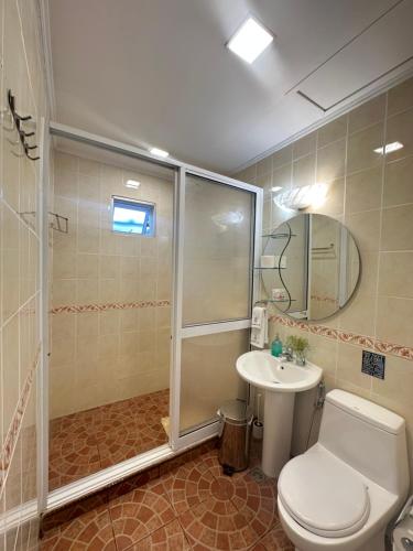 a bathroom with a shower and a toilet and a sink at Sinurambi Cottage Rental in Penampang