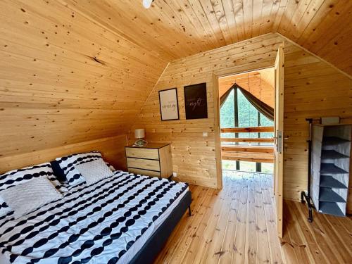 Un dormitorio con una cama en una cabaña de madera. en BalanceBay Zatoka Równowagi, en Gorzewo