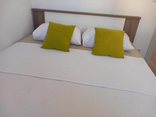 a white bed with two green pillows on it at Villa A&M in Vinišće