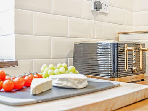 a cutting board with vegetables and cheese on a kitchen counter at 2 Bed in Oswestry 76537 in Gobowen