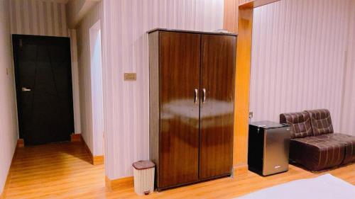 a large wooden cabinet in a room with a couch at Sapphire Suites in Karachi