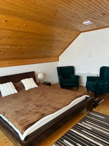 a bedroom with a large bed and two chairs at Vikendica u srcu Bjelasnice in Trnovo