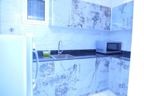 a white kitchen with a sink and a microwave at سما المملكة للشقق المخدومة- اقتصادي in Riyadh
