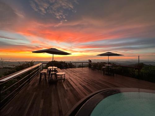 a deck with tables and umbrellas at sunset at Sinurambi Cottage Rental in Penampang